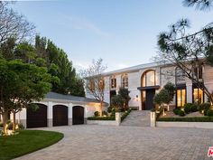 a large house with lots of trees and bushes in front of the entrance to it