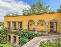 a yellow building with many windows and plants growing on it