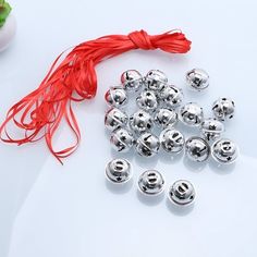 several metal bells and a red string on a white surface