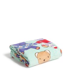 a blanket with a teddy bear on it is folded in front of a white background