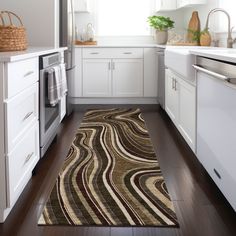 a kitchen with white cabinets and wood flooring next to an oven, microwave and dishwasher