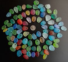 many different colored plastic objects are arranged in a circle on a black surface with a coin