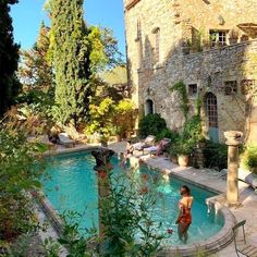 a woman standing in the middle of a swimming pool surrounded by trees and bushes,