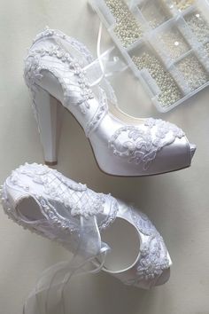 a pair of white wedding shoes sitting on top of a table