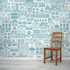 a wooden chair sitting in front of a wall with houses painted on it