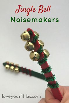 a hand holding a red and green christmas candy cane with bells on it's end