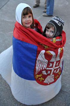 two children wrapped in a blanket on the street