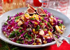 a salad with figs and other vegetables in a bowl on a red table cloth