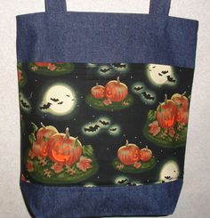 a blue tote bag with pumpkins and bats in the night sky on it