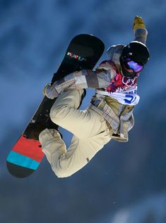 a man flying through the air while riding a snowboard in front of a blue sky