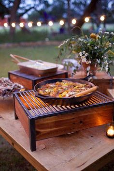 a pizza sitting on top of a wooden table next to a pot filled with flowers