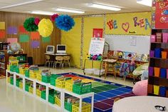 a classroom filled with lots of colorful books and decorations on the walls, including paper pom poms