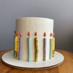 a white cake with candles on it sitting on top of a table