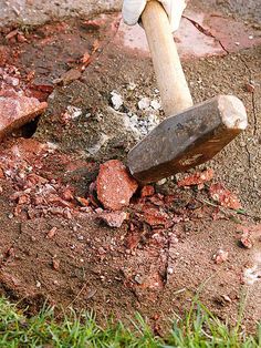 a person digging in the dirt with a large shovel and wooden handle on top of it