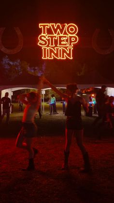 two people dancing in the dark under a neon sign that reads, two step inn