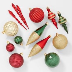 a collection of christmas ornaments arranged on a white surface with red, green and gold decorations