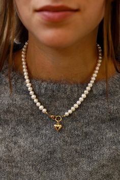 This freshwater pearl necklace features a central clasp with a gold puff heart. Style it with the emory heart necklace featured in the second photo for a love filled look. Details: - Freshwater pearls - Gold filled clasp - Gold plate brass heart charm - 16.5" length SKU: N1100G Materials+Care