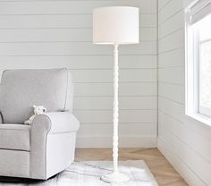 a white lamp sitting next to a chair in a room