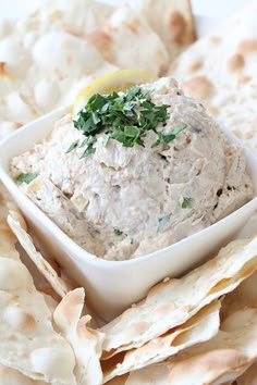 a white bowl filled with dip surrounded by tortilla chips