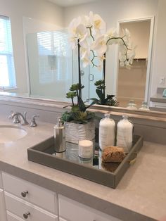 a bathroom sink with soap, lotion and flowers in the tray next to it