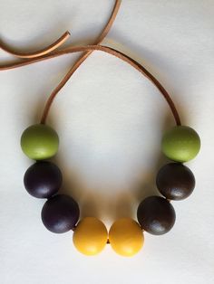 a necklace made out of wooden beads on a brown leather cord with green and yellow beads