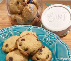 chocolate chip cookies are on a blue plate next to a jar of empty milk bottles