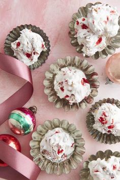 several cupcakes with white frosting and sprinkles next to a pink ribbon