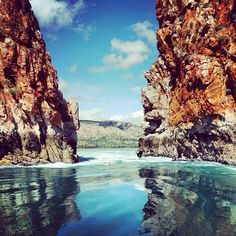 the water is crystal blue and there are some rocks in the background that look like they have been cut off