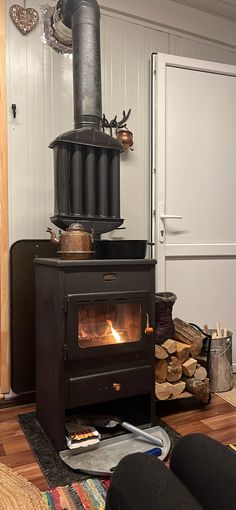 a wood burning stove in a living room next to a pile of logs and firewood