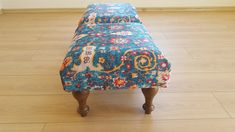 a blue floral bench sitting on top of a hard wood floor