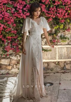 a woman standing in front of flowers wearing a white dress