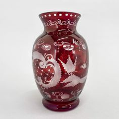 a red glass vase with white designs on it