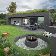 an outdoor living area with grass on the roof and fire pit in the middle of it