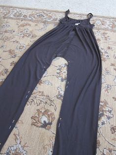 a woman's black jumpsuit laying on top of a rug