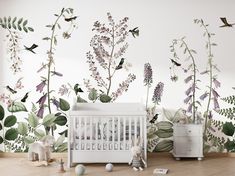 a white crib in front of a wall with flowers and birds painted on it