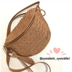 a straw bag with a tasseled strap and zippers on the bottom is sitting on a white surface