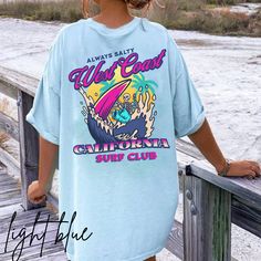 California surf T-shirt. Skeleton surfing on the back with a small pocket design in front. Perfect tee to wear this summer or all year round. Perfectly preppy attire. To wear this oversized, size up 1-2 sizes. *Unisex sizing. Please see size chart in photos*  No side seams mean there are no itchy interruptions under the arms. The shoulders have tape for improved durability. .: 100% cotton (fiber content may vary for different colors) .: Medium fabric (5.3 oz/yd² (180 g/m .: Classic fit .: Tear-away label .: Runs true to size Summer Crew Neck Top With Back Print, Blue Beach T-shirt With Front Print, Blue Summer T-shirt For Surfing, Summer Streetwear Tops With Back Print, Relaxed Fit T-shirt With Back Print For Summer, Trendy Cotton T-shirt For Surfing, Oversized T-shirt With Back Print For Summer, Summer Cotton Tops With Back Print, Cotton Tops With Back Print For Summer