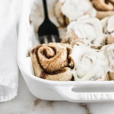 cinnamon rolls with icing in a white dish