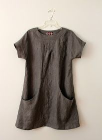 a gray dress hanging on a white wall with a hanger attached to it's side