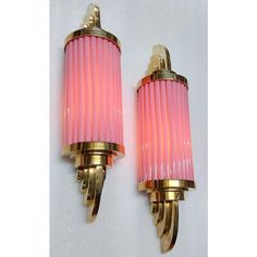 two pink and gold sconces mounted on a wall