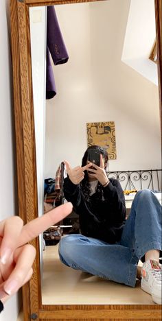 a woman taking a selfie in front of a mirror with her hand up to the camera