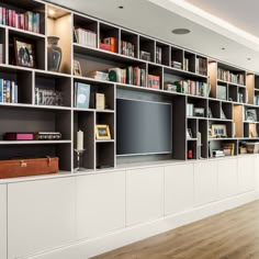 a living room filled with lots of white bookshelves and a flat screen tv