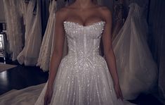 a woman in a wedding dress standing in front of dresses