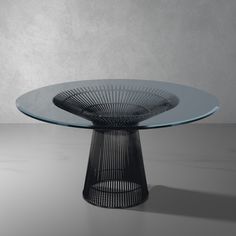 an oval glass table with metal base on a gray background, in the shape of a bird's nest