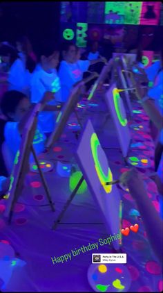 a group of people sitting at a table with neon lights on it and one person standing in front of them