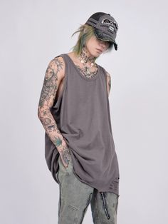 a man with tattoos wearing a baseball cap and tank top standing in front of a white background