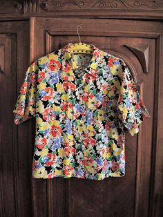 Beautiful Vintage short sleeve blouse from the 1980s. Comfortable cotton fabric with a vibrant summer floral pattern. Straight, boxy cut, wide sleeves, button down. Looks great with a pair of jeans and flatform sandals. BRAND: C&A ERA: 1980s COLOR: White, black, green, yellow, red, lilac FABRIC: 100% cotton SIZE: No size tag, fits best size M to small L (or S for a more oversized fit) - please check measurements below for reference MEASUREMENTS: Pit to pit 54cm, total length 60cm CONDITION: Vintage Patterned Shirt For Summer, Patterned Vintage Shirt For Summer, Multicolor Floral Print Short Sleeve Shirt For Spring, Spring Vintage Print Hawaiian Shirt With Short Sleeves, Vintage Print Short Sleeve Hawaiian Shirt For Spring, Vintage Print Hawaiian Shirt For Spring, Spring Short Sleeve Shirt With Floral Print, Vintage Cotton Hawaiian Shirt For Summer, Multicolor Floral Print Short Sleeve Shirt For Summer