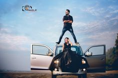 a man standing on the hood of a pickup truck next to a woman in a black dress