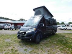 a camper van parked in a parking lot next to other cars and trucks on the grass