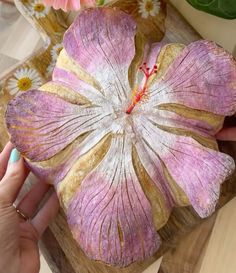 a person holding a flower shaped object on top of a wooden table